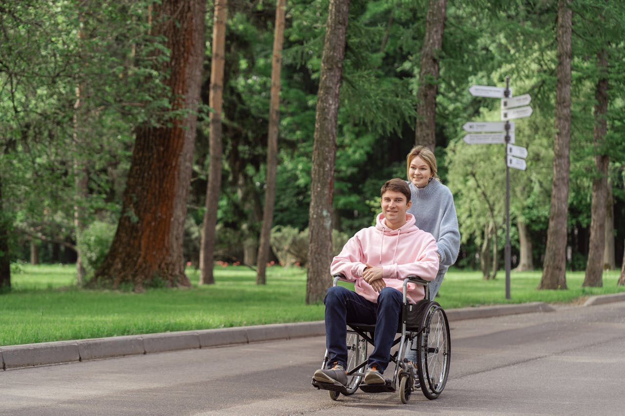 Photo by SHVETS production: https://www.pexels.com/photo/woman-pushing-the-wheelchair-with-a-man-8415730/